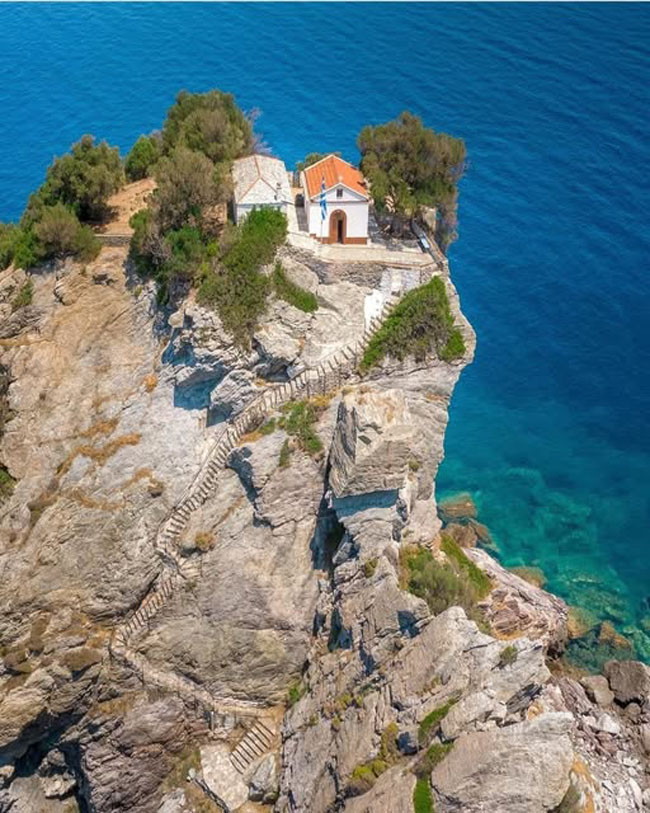 Agios Ioannis Chapel perched on top of a rugged Greek cliff. 