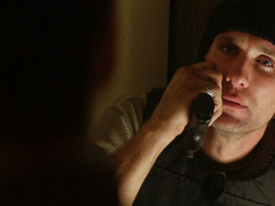 Actor Peter Greene looking mean and holding a gun while wearing a black woollen hat in the film Training Day.