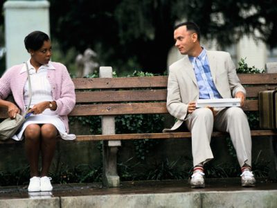 Tom Hanks sitting on a park bench talking to a female nurse who is sat next to him in the film Forrest Gump