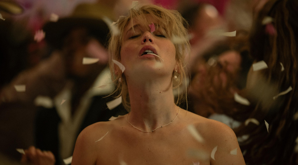 Jennifer Lawrence in the film Die My Love with her eyes closed and her head facing up as confetti rains down in a ballroom.