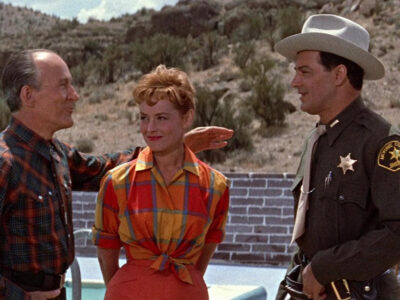 A vibrant 2.55:1 CinemaScope still from Edge of Eternity featuring Cornel Wilde and Victoria Shaw against a desert backdrop.