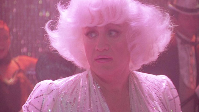 Gene Hackman, bathed in a pink glow thanks to a pink wig and sparkly white clothing, is seen in drag in the film, The Birdcage. 