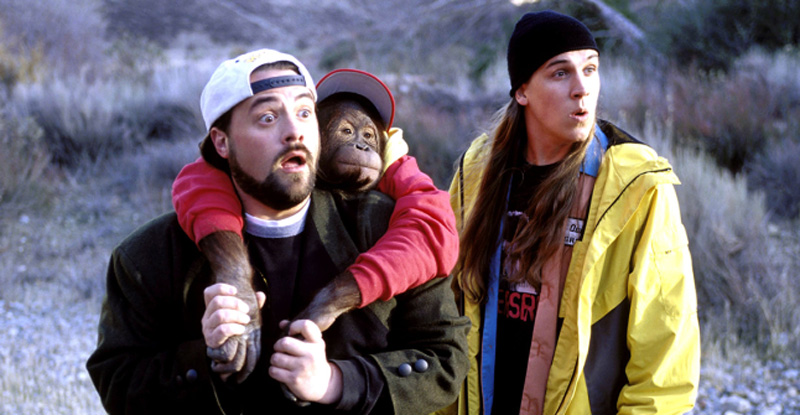 Kevin Smith as Silent Bob with a chimpanzee on his back looking shocked standing next to Jason Mewes as Jay in the film Jay and Silent Bob Strike Back - early 2000s comedy movies