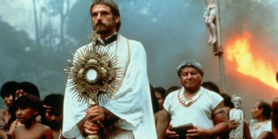 Jeremy Irons holding a religious staff and wearing a white cloak in the film, The Mission.