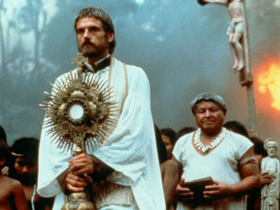 Jeremy Irons holding a religious staff and wearing a white cloak in the film, The Mission.
