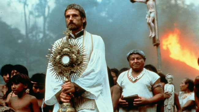 Jeremy Irons holding a religious staff and wearing a white cloak in the film, The Mission.