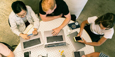 People at a desk with laptops seen from above.