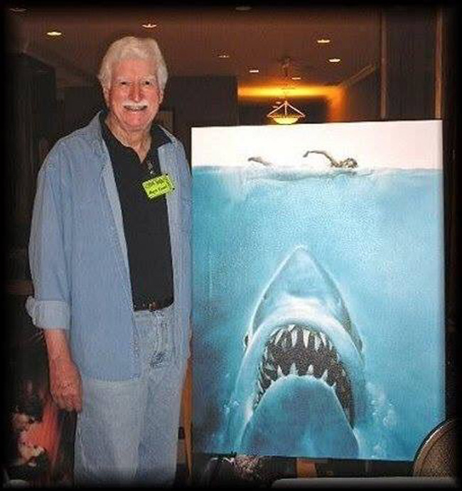 Roger Kastel, Jaws poster artist, stands next to the film's poster