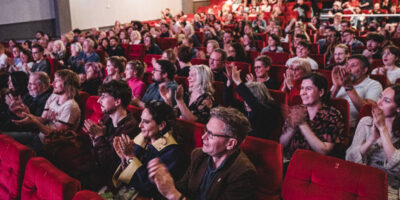 Sheffielf DocFest generic audience image showing cinema audience in red seats clapping after the house lights have come up.