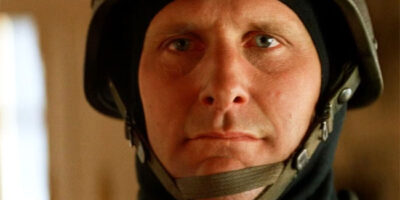 Jeff Daniels, in close-up, staring at the camera wearing a police SWAT helmet in the film Speed.