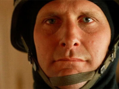 Jeff Daniels, in close-up, staring at the camera wearing a police SWAT helmet in the film Speed.